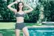 A woman in a bikini standing next to a swimming pool.