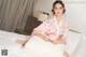 A woman in a pink kimono sitting on a bed.