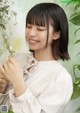 A woman in a white blouse holding a plant.