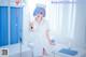 A woman dressed as a nurse holding a syringe in a hospital room.