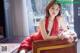 A woman in a red dress sitting on a brown chair.