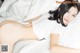 A woman laying on top of a bed in a white shirt.