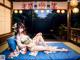 A woman in a kimono sitting on a blue mat.