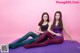 Two young women sitting on a purple yoga mat.