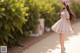 A woman in a white dress and hat walking down a sidewalk.