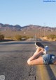 A woman laying on the side of a road with her feet up.